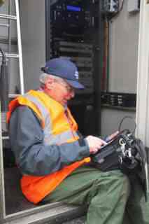 Engineer in a hi‑visibility vest working on RF equipment inside a transmitter enclosure.